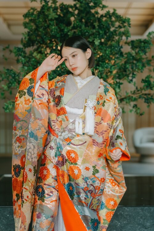 YK16の色打掛姿で振り返る花嫁、豪華な花柄の裾模様