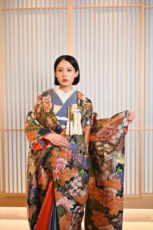 オレンジと紺の花々があしらわれた華やかな振袖姿で佇む花嫁