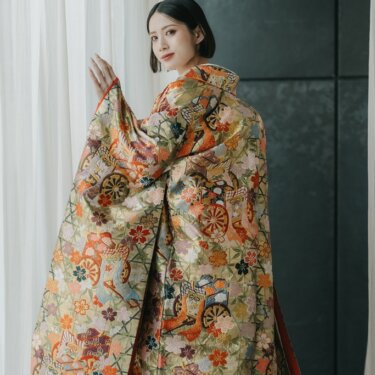 白いカーテンの窓辺で振り返る、御所車柄の金色の色打掛の花嫁。和装前撮りのスタジオフォト