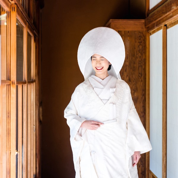白い綿帽子をかぶり、白無垢姿で微笑む花嫁