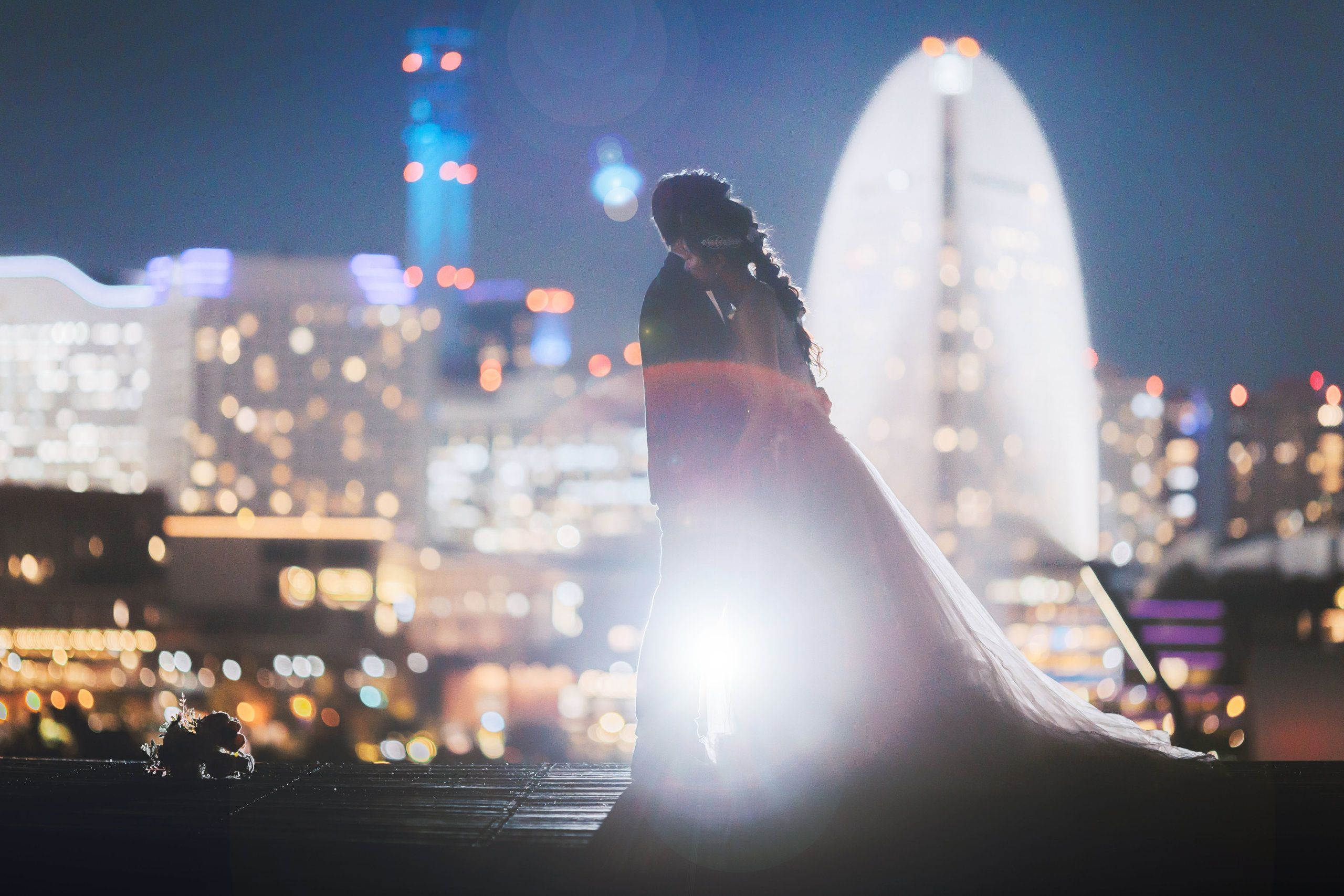 大さん橋の夜景を背景に口づけを交わすシルエットの新郎新婦、横浜のビル群を望む夜のロマンチックな一枚