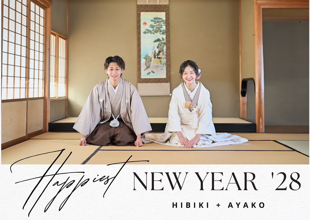 和室で床の間を背景に正座する、灰茶の羽織袴と白無垢姿の新郎新婦の年賀状デザイン
