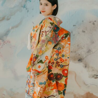 アートウォールを背に振り返る色打掛姿の花嫁。オレンジと金の花丸文様が華やかなスタジオ和装前撮り