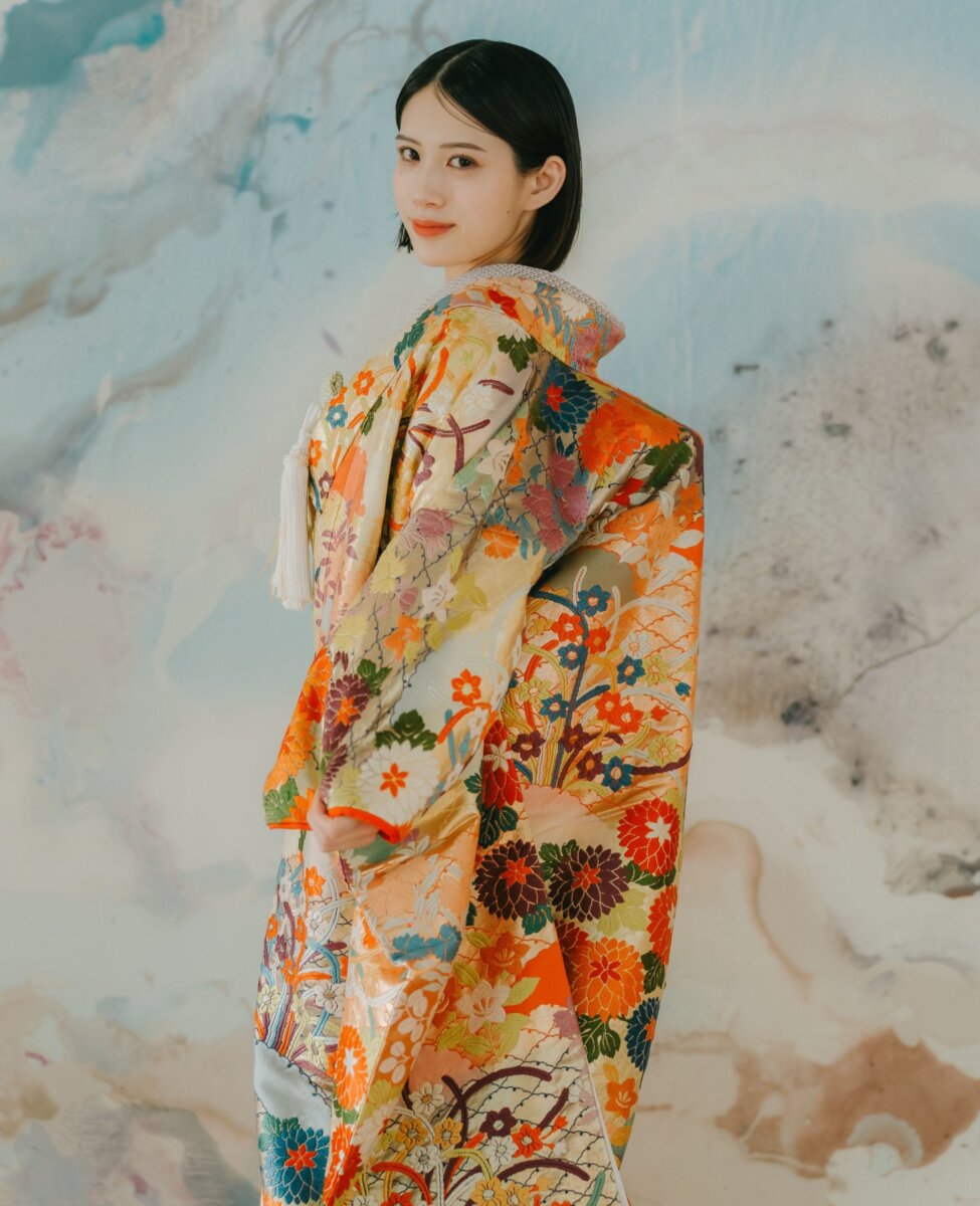 アートウォールを背に振り返る色打掛姿の花嫁。オレンジと金の花丸文様が華やかなスタジオ和装前撮り