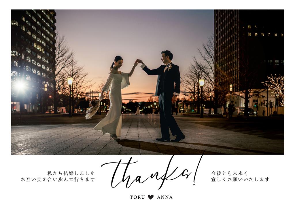 高層ビル街の夕暮れの広場でダンスを踊る新郎新婦の結婚報告ハガキデザイン