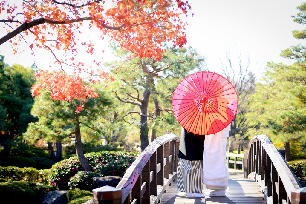 名古屋の徳川園で緑と紅葉が混ざる庭園を背景にした和装の新郎新婦。秋の初めに撮る和装前撮りフォトウェディング