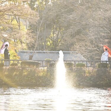 噴水のある池をはさんで和傘を手に向かい合う白無垢の新婦と紋付袴の新郎。冬の澄んだ光に包まれる和装前撮り