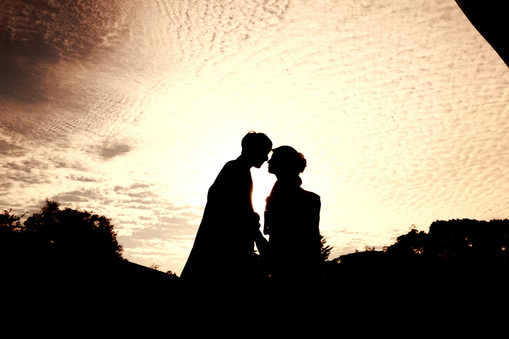 冬の澄んだ空の下で向き合うタキシードの新郎とウェディングドレスの新婦。冬の前撮りらしい透明感のあるロケーションフォト